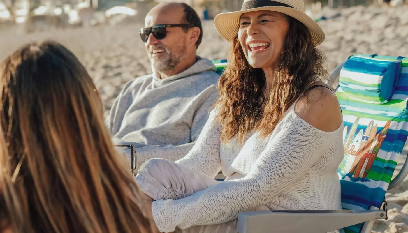 Lachende man en vrouw op strandstoelen. De zon schijnt en ze zitten op het strand.