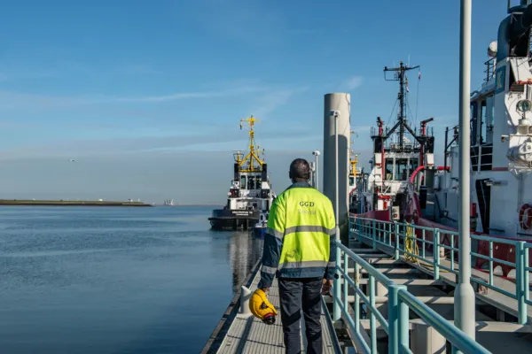 Man loopt op steiger naast een boot