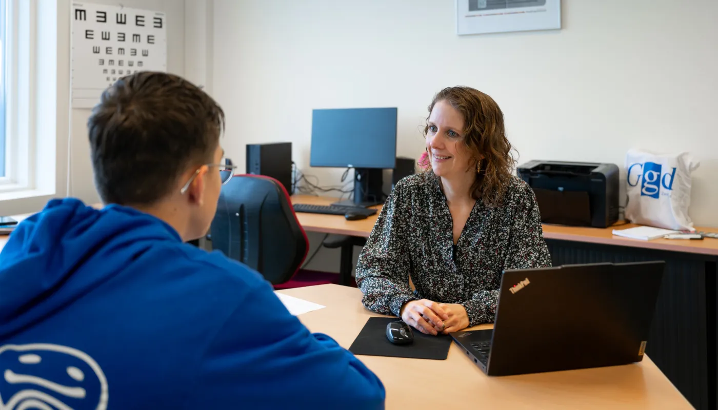 Jeugdverpleegkundige van GGD Zeeland op middelbare school. De jeugdverpleegkundige neemt een gesprek af met een scholier.