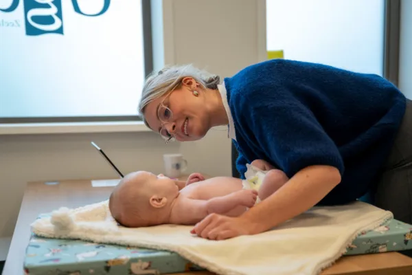 GGD medewerker kijkt in het oortje van een baby op het consultatiebureau.