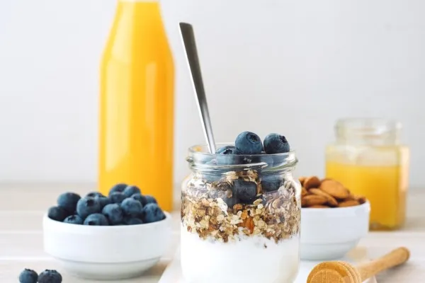 Foto van gezond eten. Een fles sinaasappelsap, yoghurt met blauwe bessen en haver.