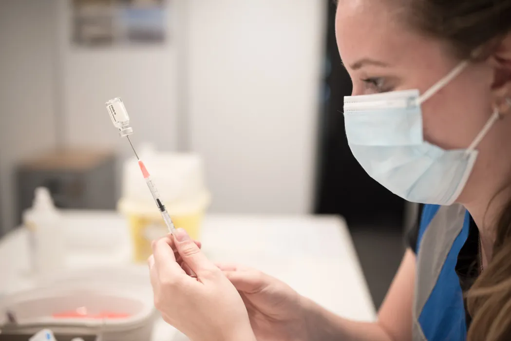 Medewerker van de GGD is bezig met het optrekken van het covid vaccin.